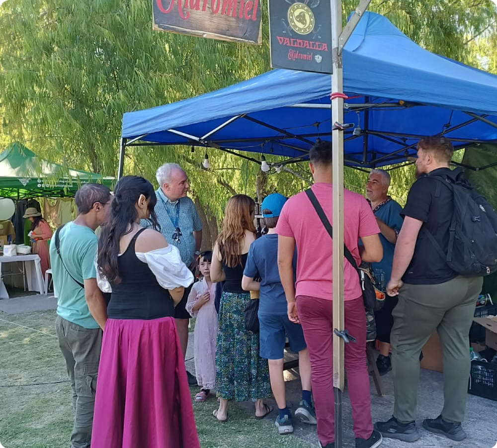 Stand rodeado de personas en un evento medieval charlando y degustando hidromiel